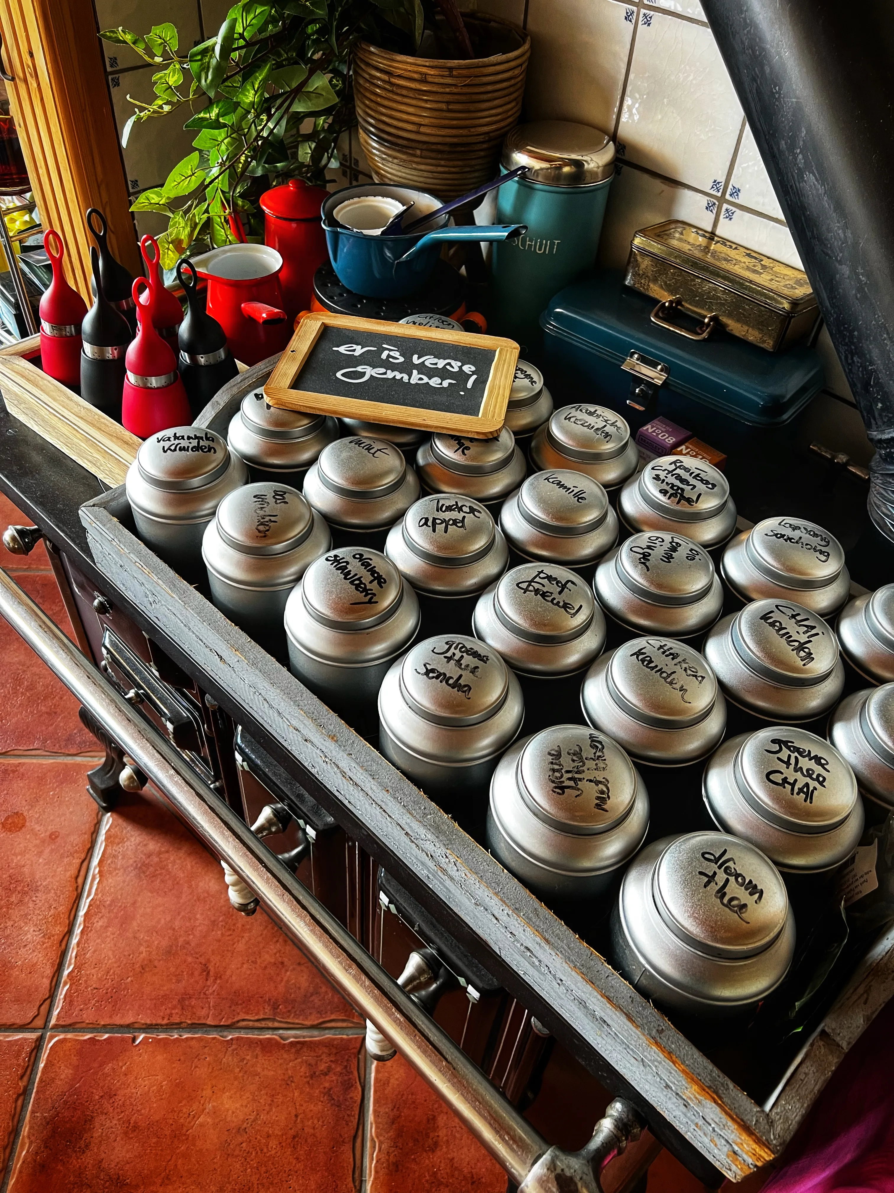 Detail van een verzameling thee in blikjes met handgeschreven labels op de ontbijttafel