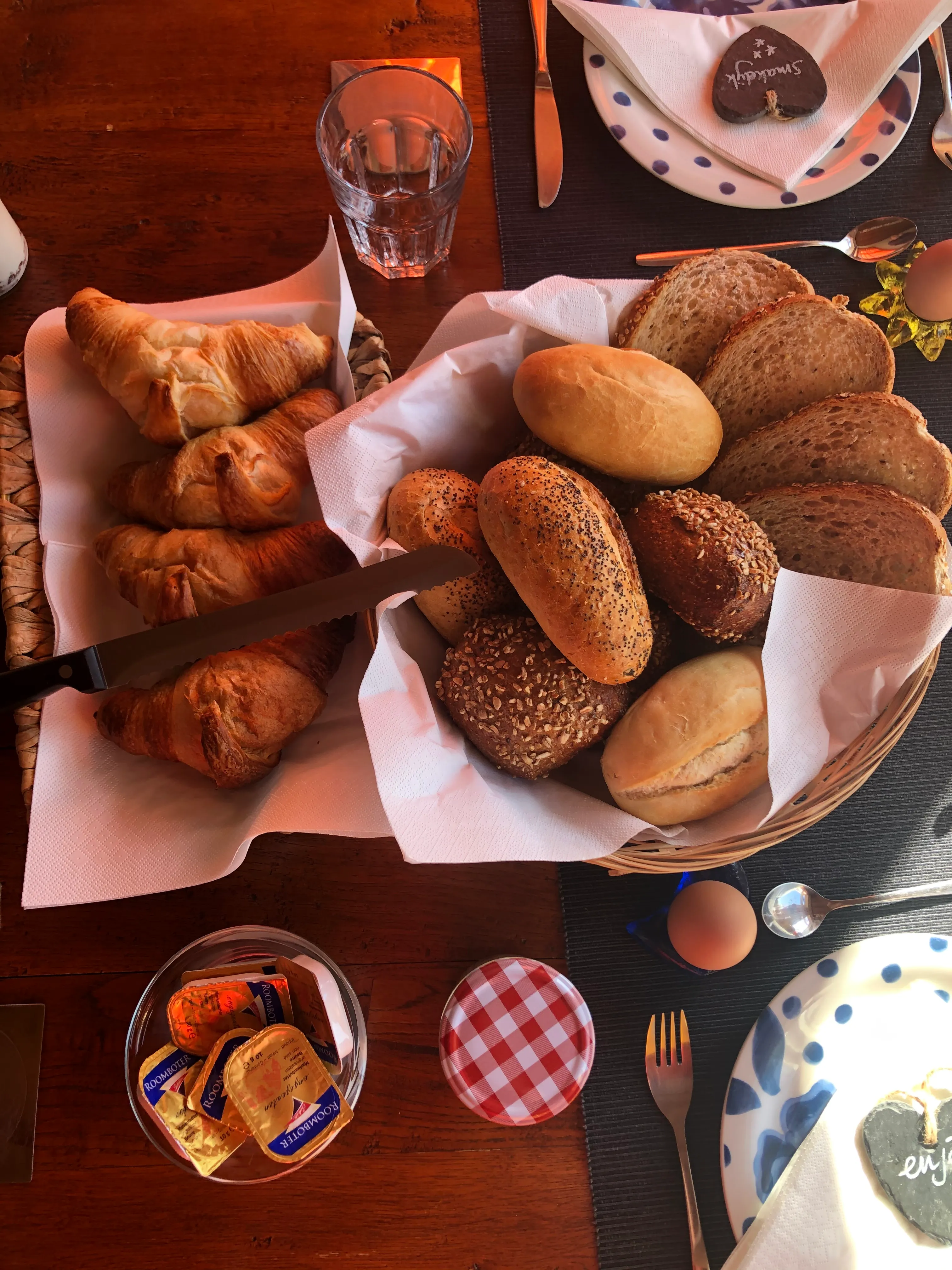 Rijk gedekte ontbijttafel met verse broodjes, croissants en een gekookt eitje